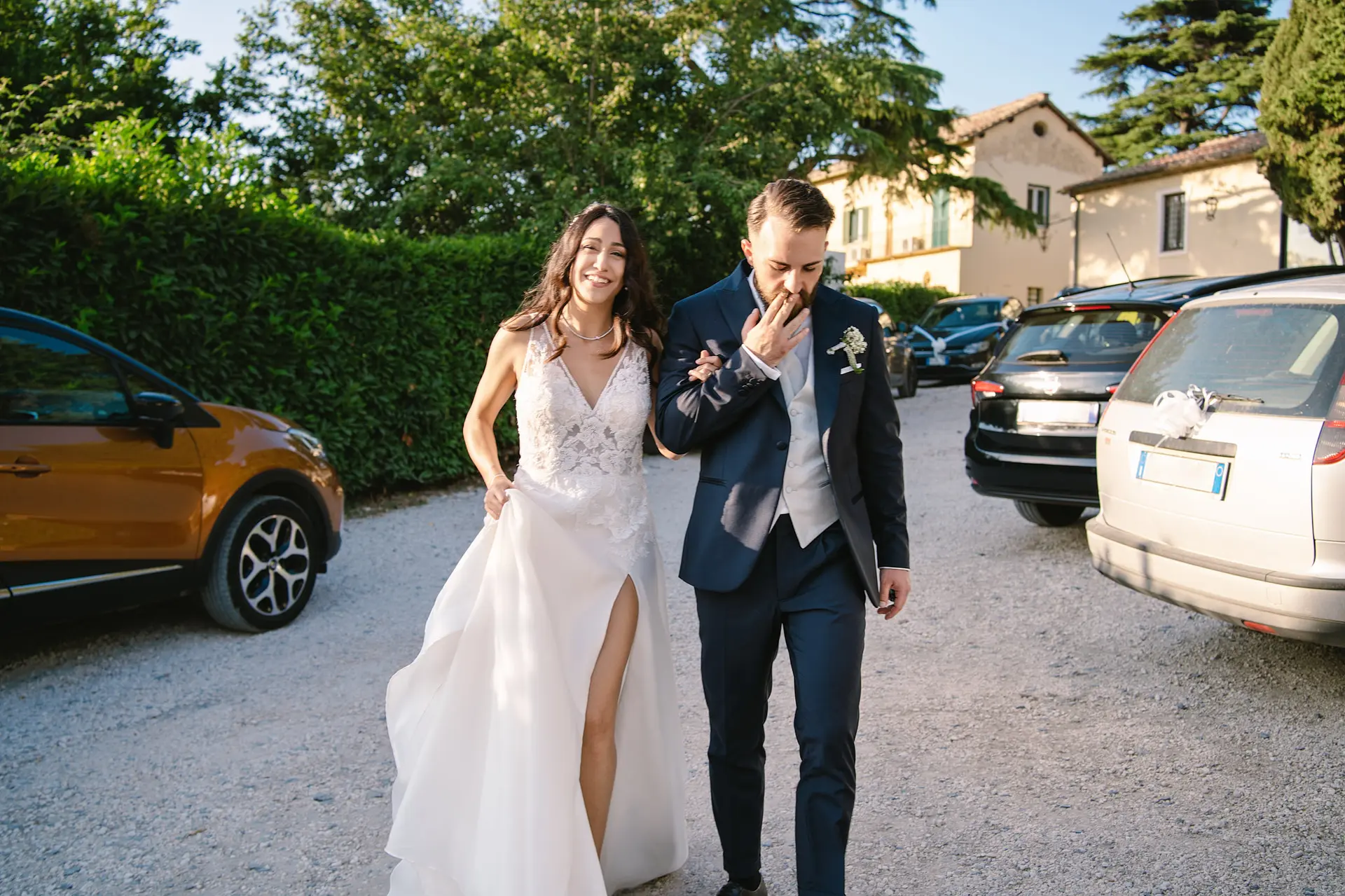 Cheerful bride and groom walking hand-in-hand on their sunny Italian wedding day celebration, happy times.