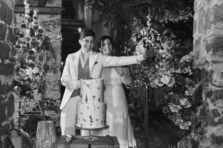 Two smiling brides take selfie at vegan wedding, multi tiered cake and romance are there.