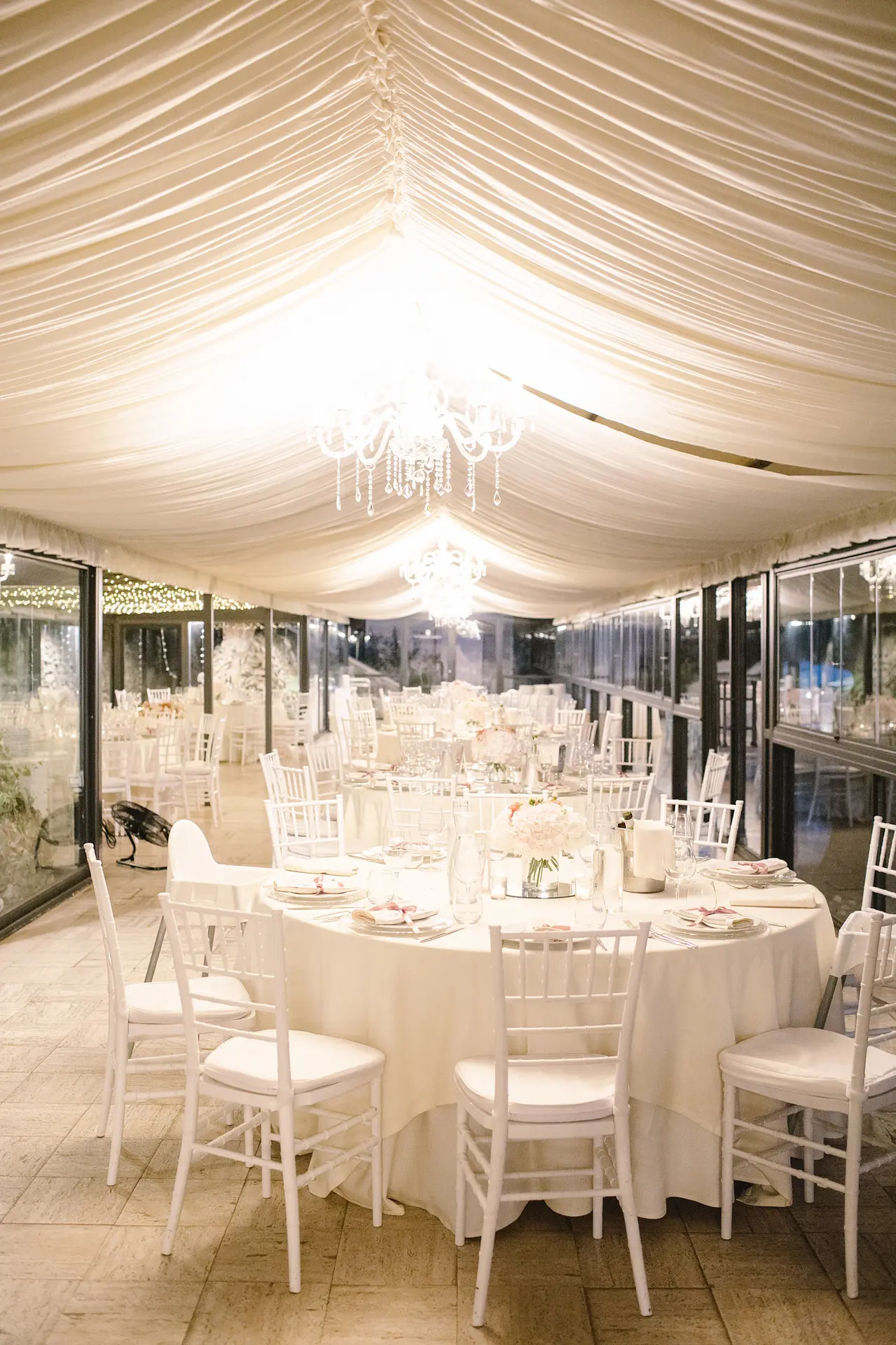 Elegant chandeliers and tables ready for the wedding rehearsal reception under large tent structure.