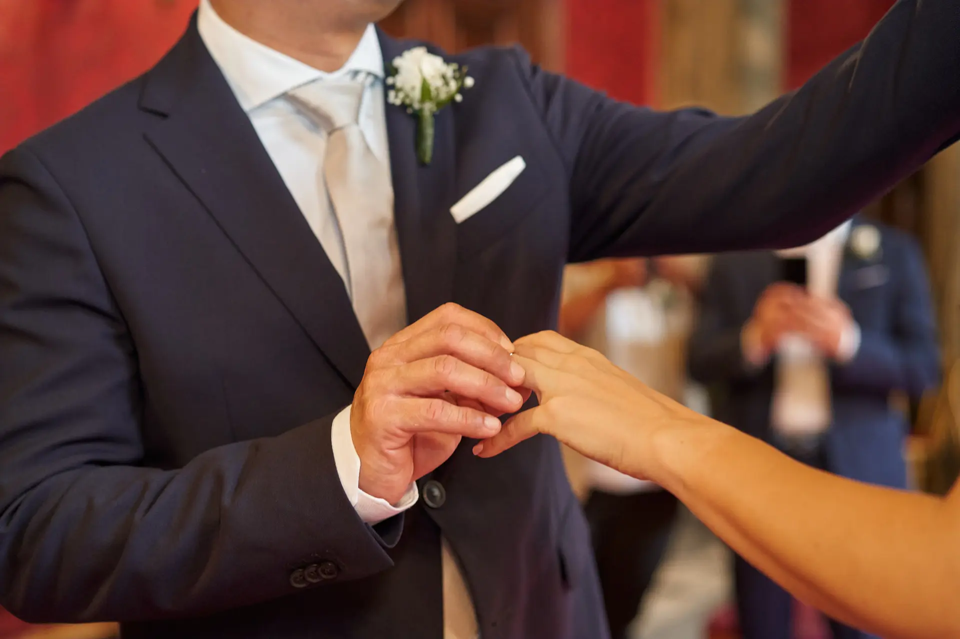Groom putting ring on bride, consider which finger to wear wedding ring.
