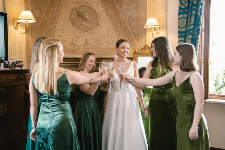 Bride in white toasts with bridesmaids in green. Ideas for how to ask someone to be your bridesmaid.