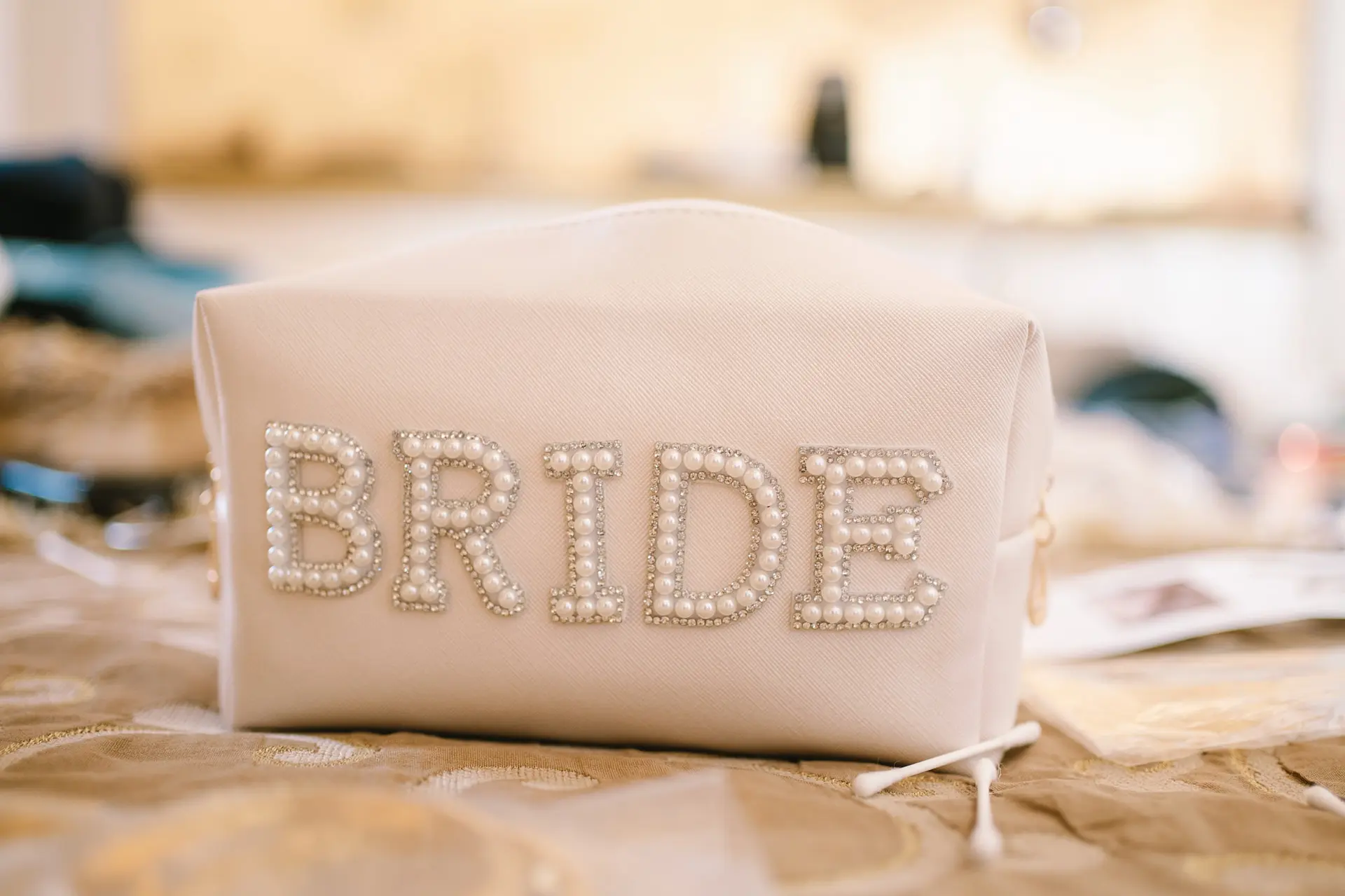 Close-up of a white pouch with the word "BRIDE" elegantly spelled out in pearls.