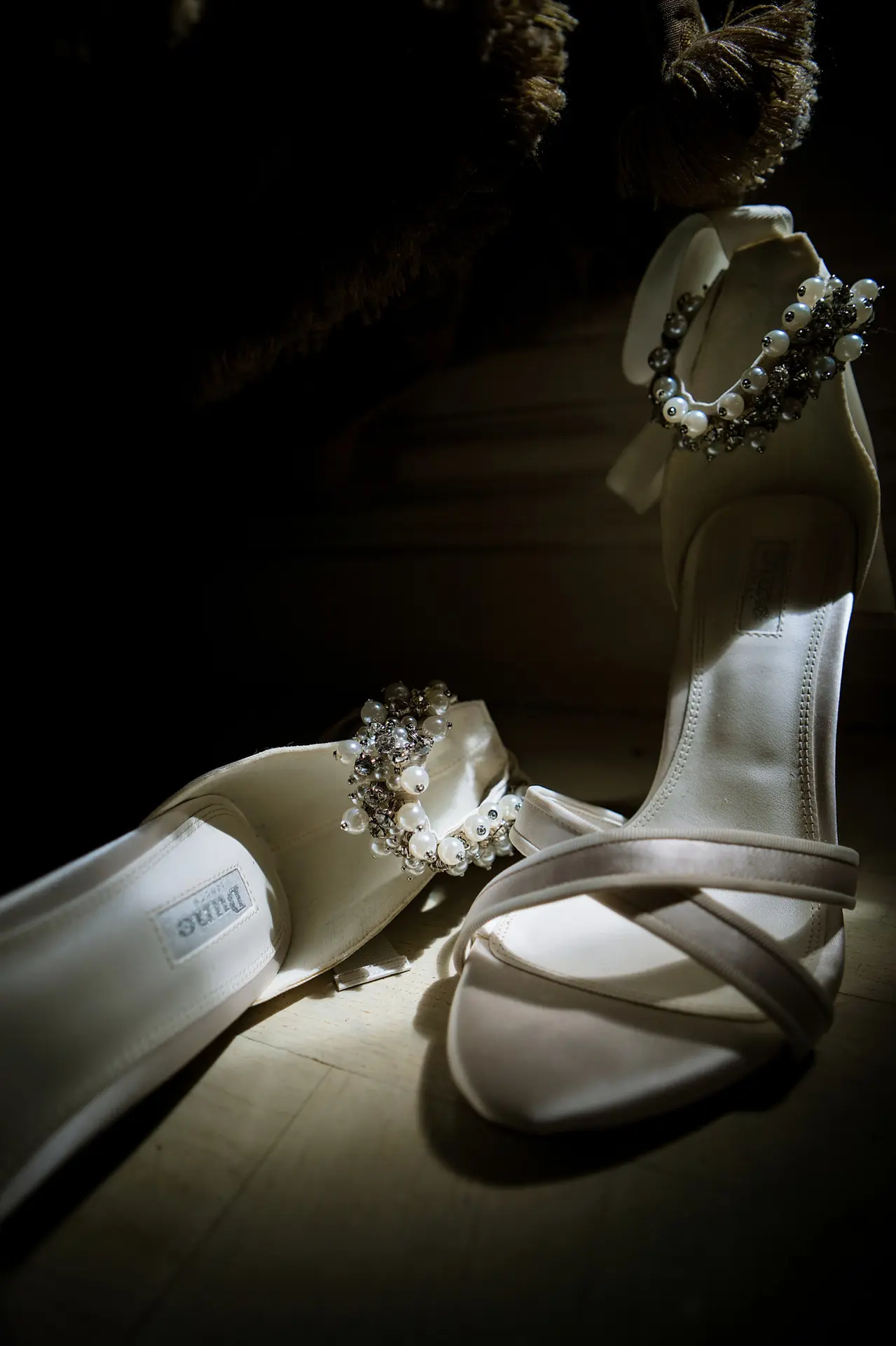 Elegant white high-heeled wedding shoes featuring pearl details on the ankle straps.