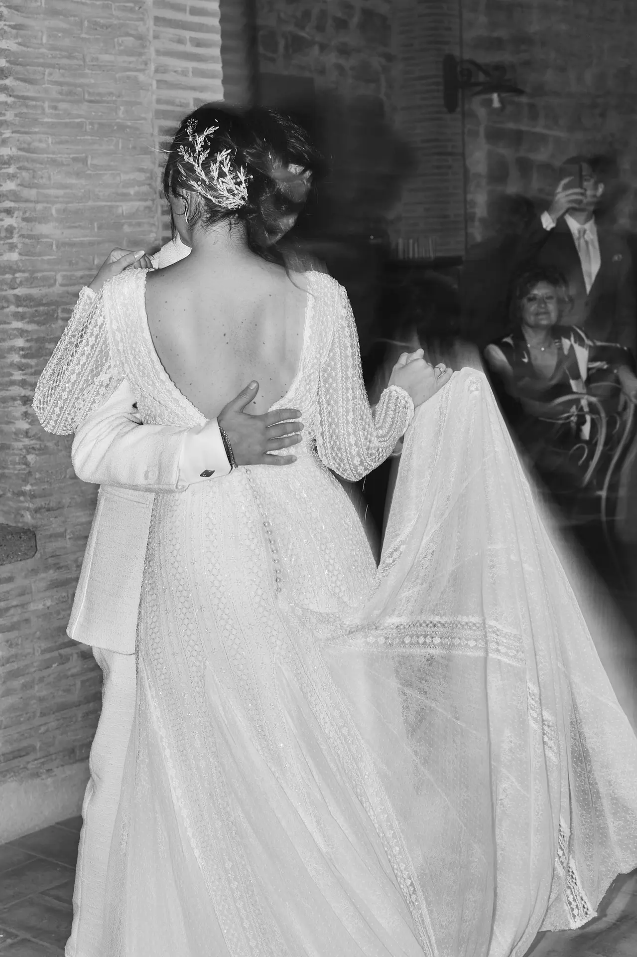 B&W: Couple dances intimately to Italian wedding music, her detailed low-back dress swirls.