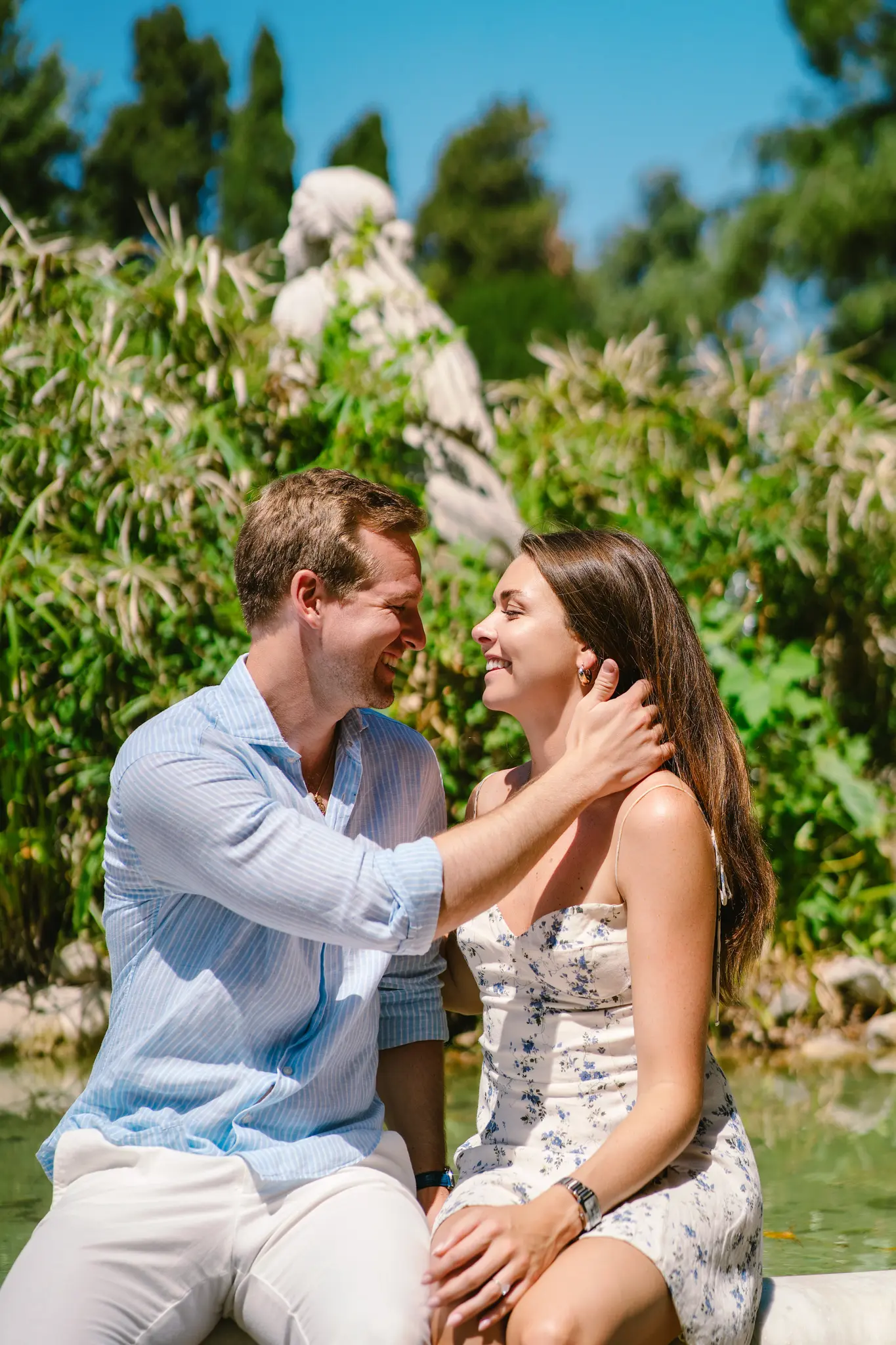 A smiling couple looks at each other in Villa Borghese after getting engaged.