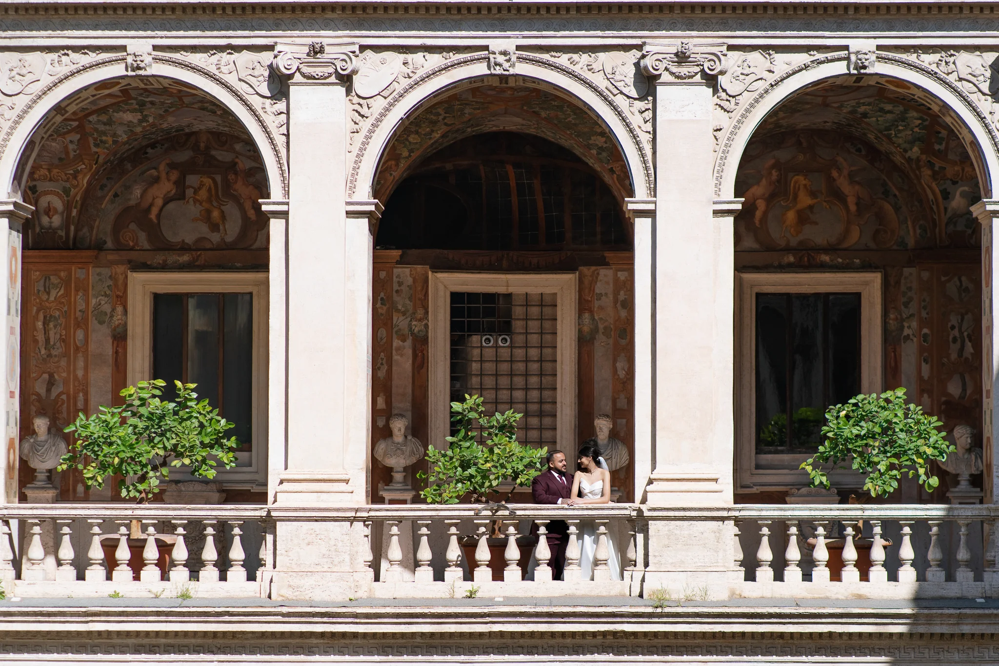 A couple stands on an ornate Italianate balcony with grand arches, a stunning engagement photo location.