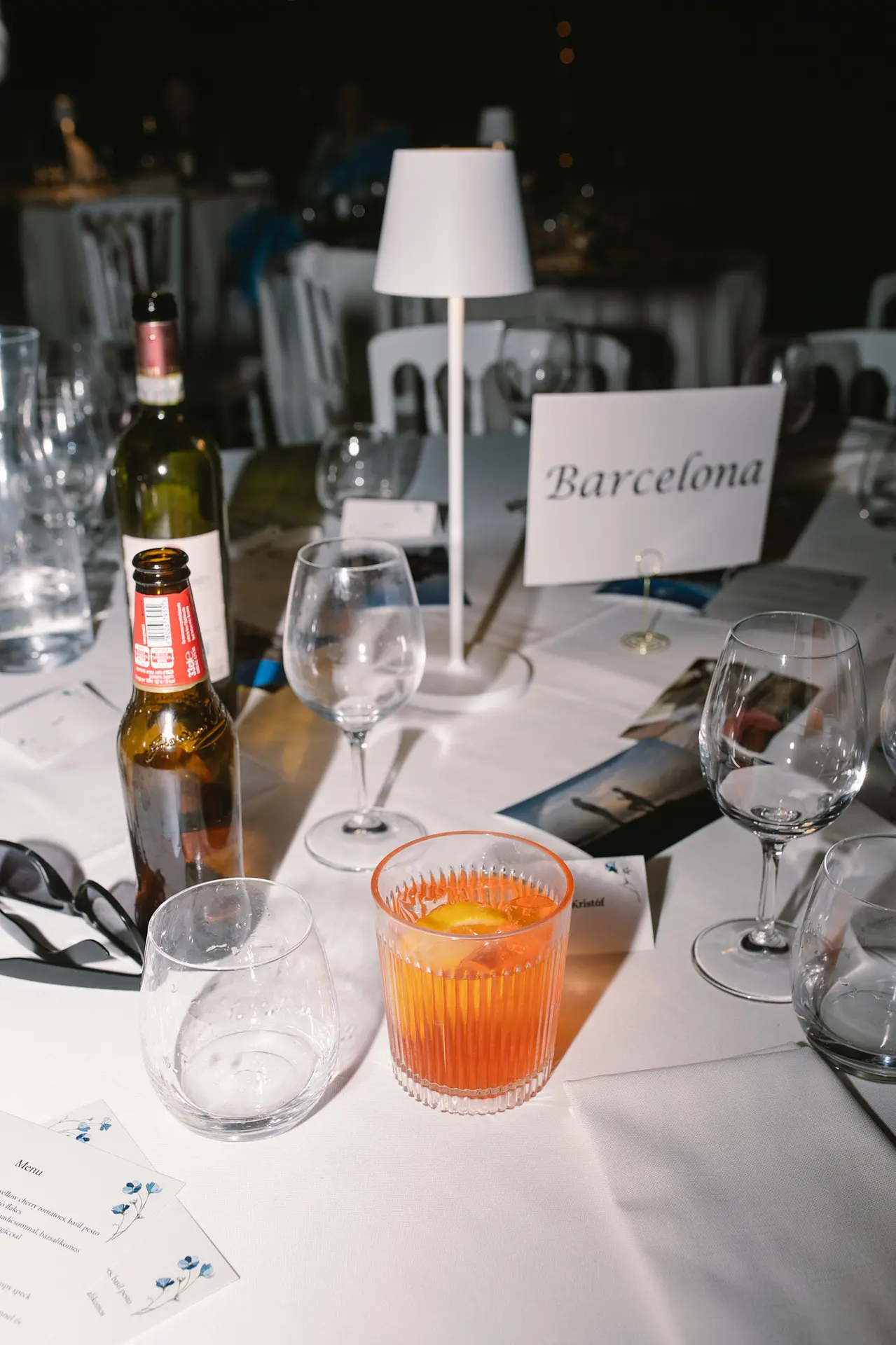 Wedding table setting with drinks, glasses, a menu, and a "Barcelona" place card.
