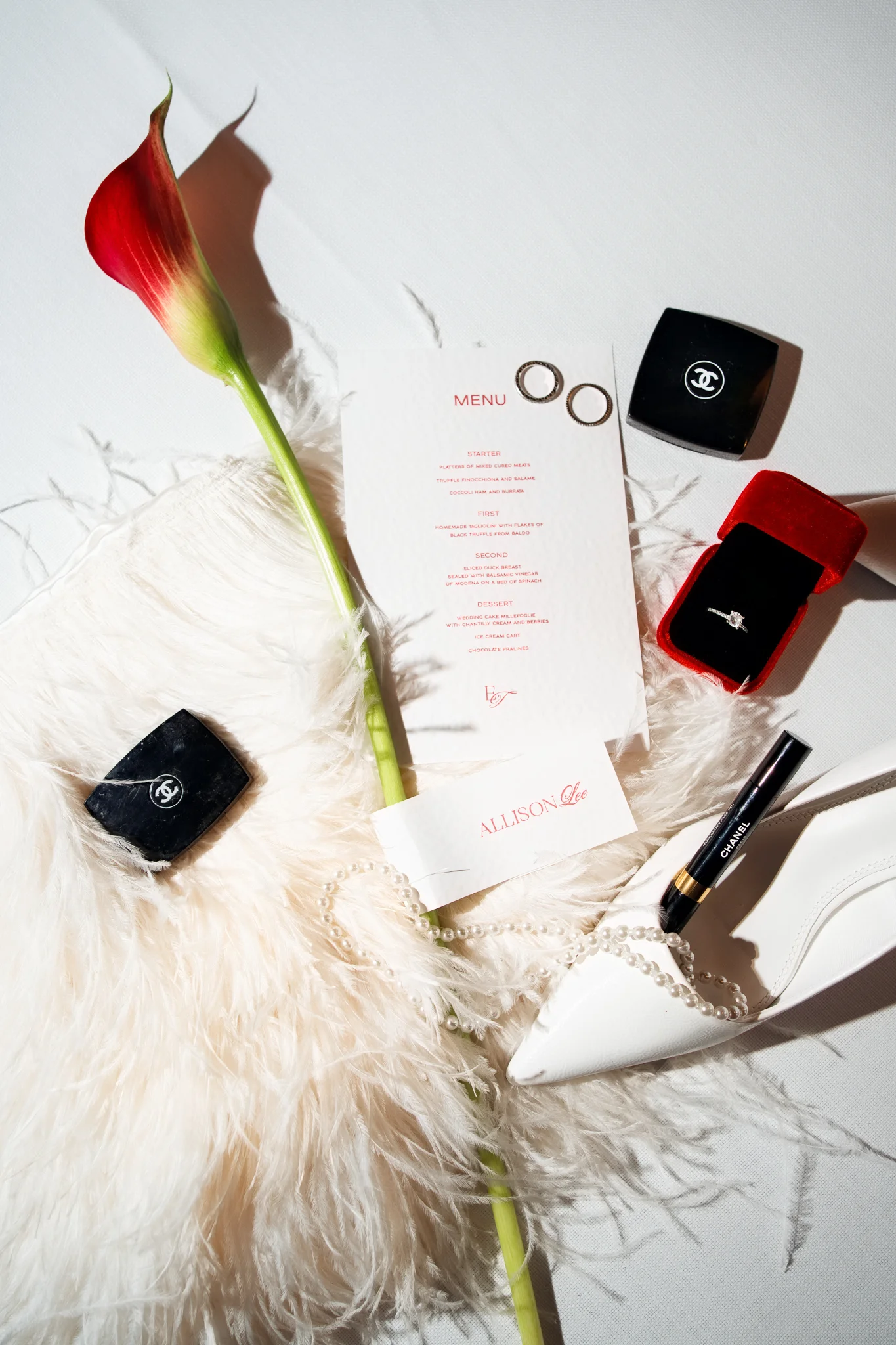 A stylish flat lay with a menu, ring, and calla lily, a guide on how to make Italian wedding invitations.