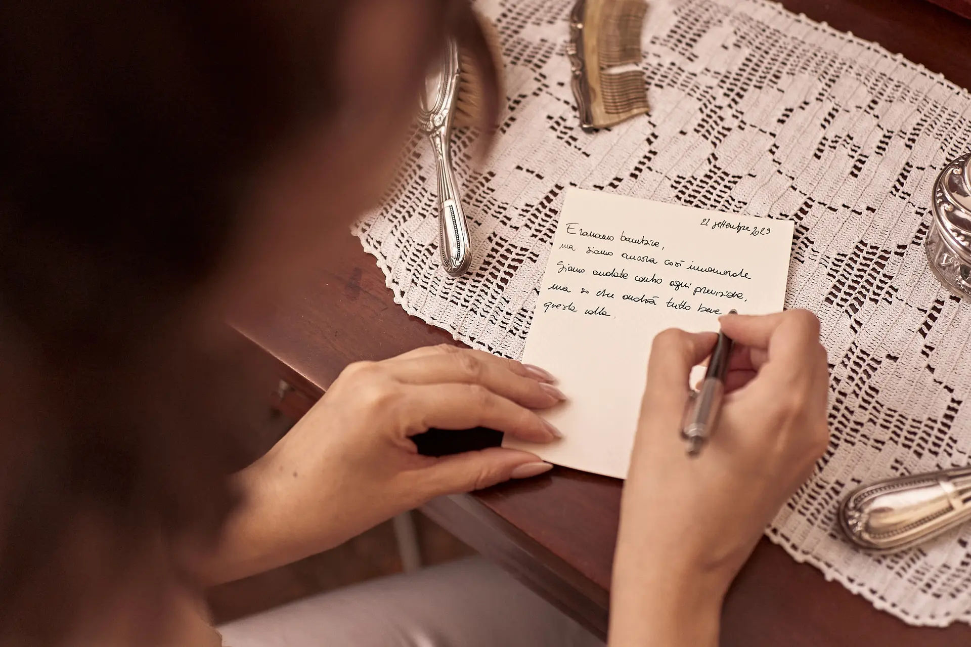 A woman writes a note in Italian, showing how to make an Italian wedding invitations feel personal.