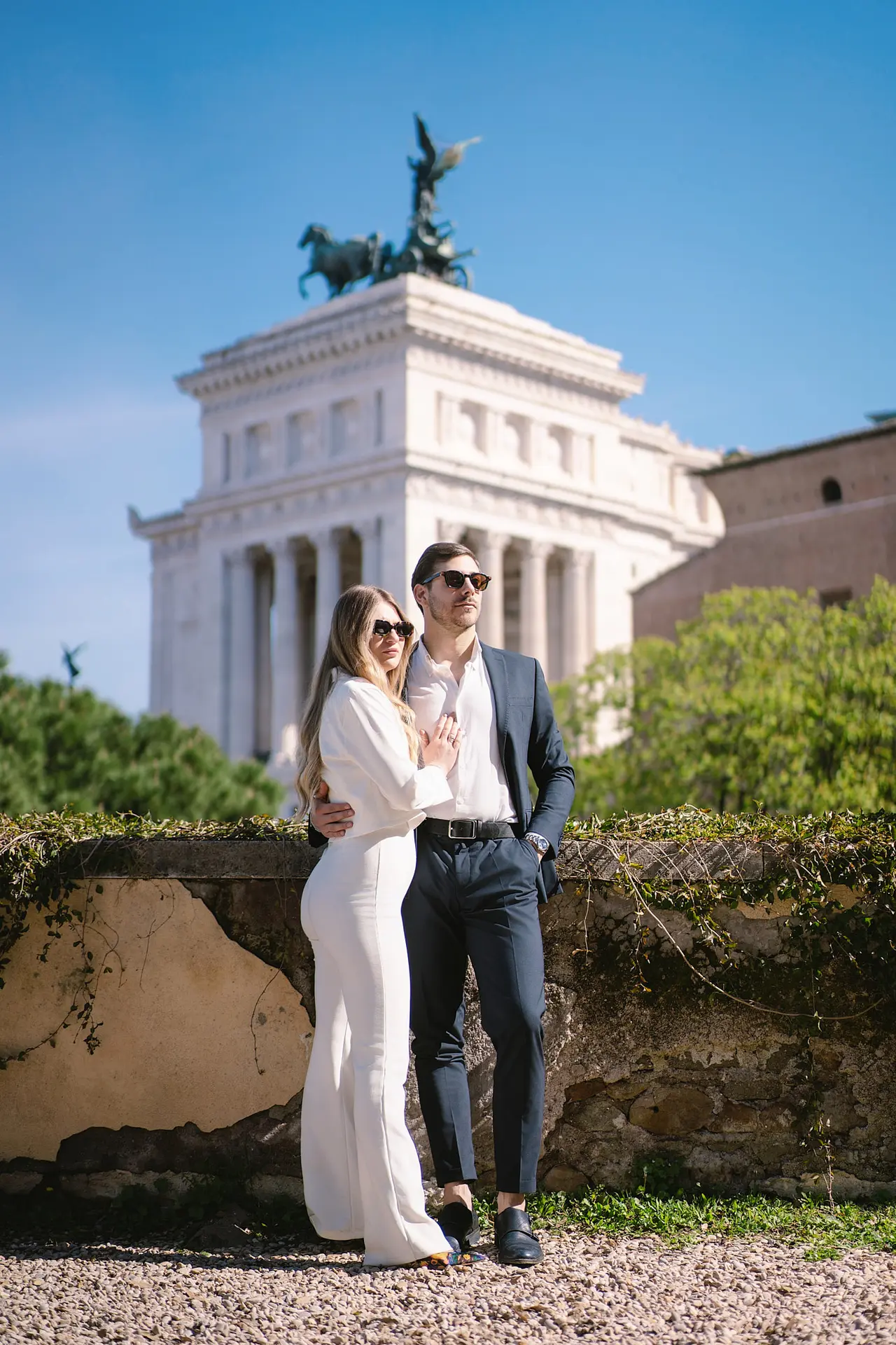 A professional photographer for Italy weddings captures a stylish couple posing in Rome with the Altare della Patria behind them.