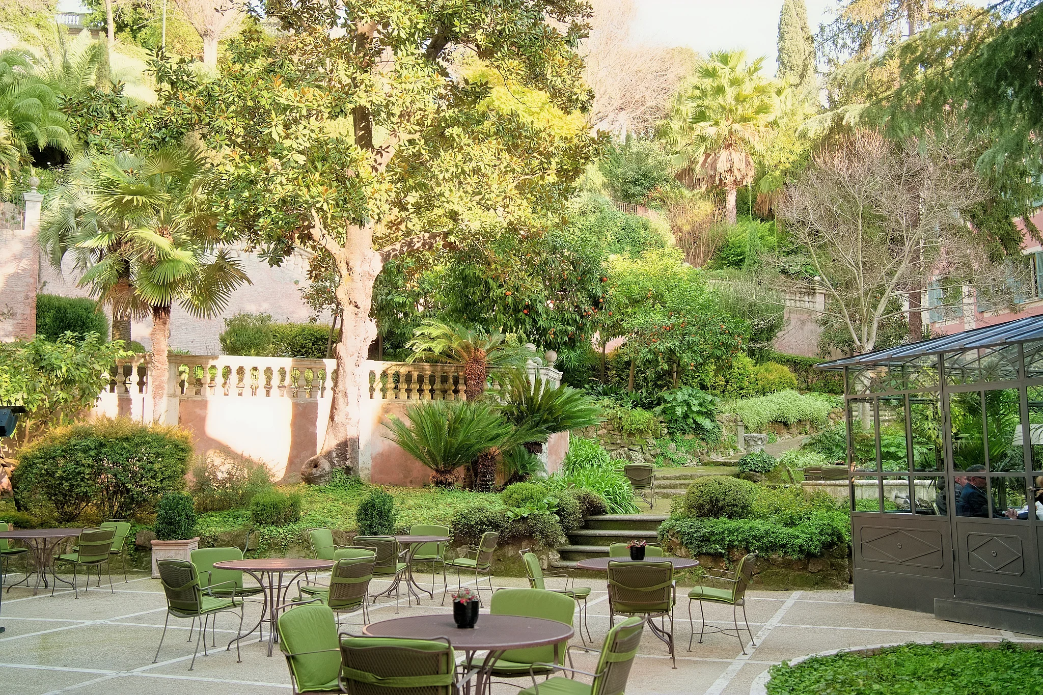A serene Italian garden terrace with green chairs and tables, ready for a wedding reception.