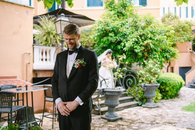 A groom smiles as he waits for the first look, a candid moment captured by a wedding second shooter in Italy.