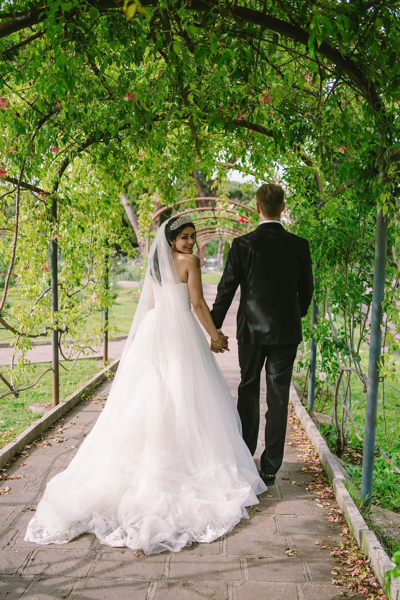 Bride smiles at her affordable destination wedding in Italy while walking under a green arch.