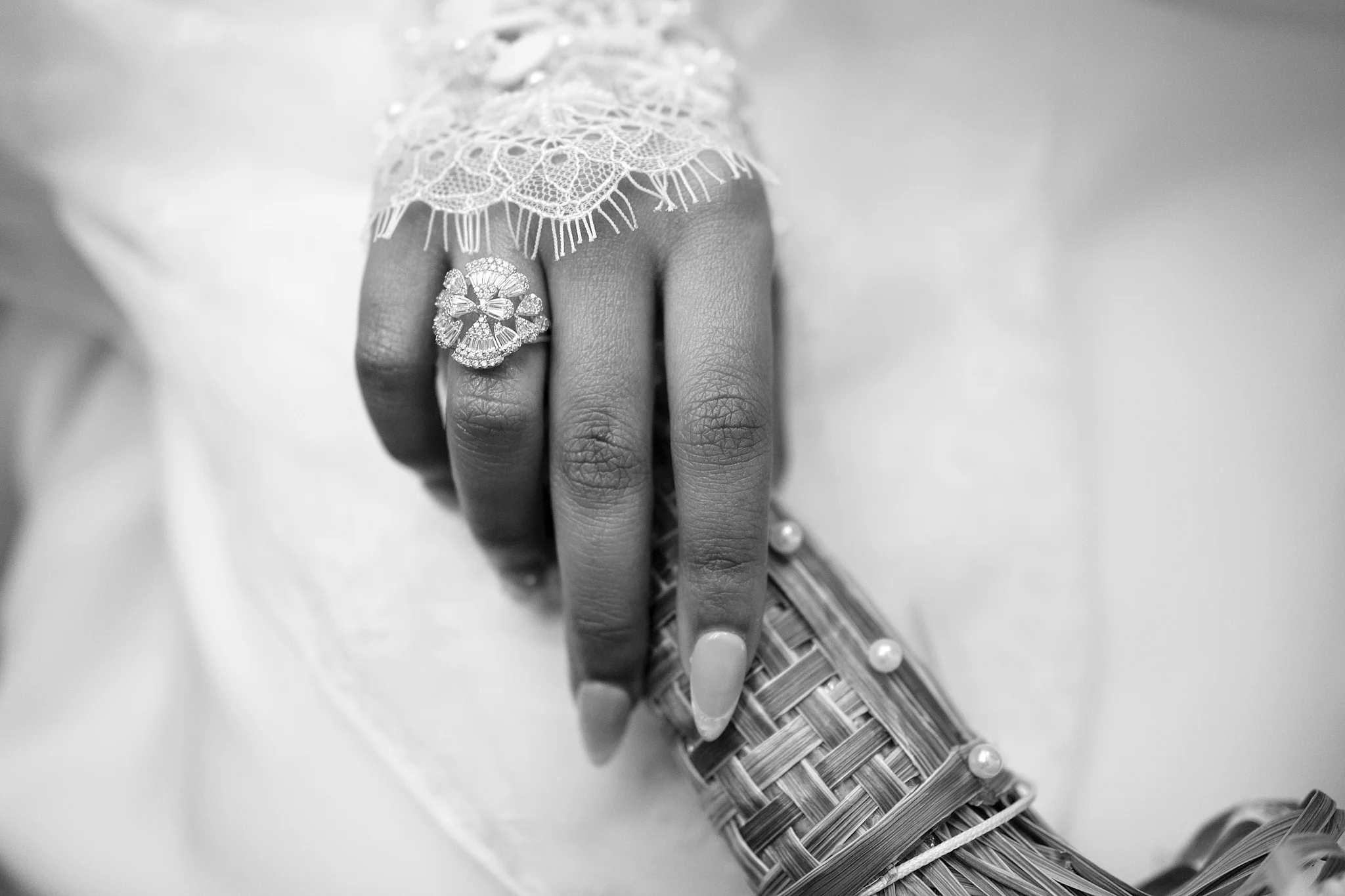 Black and white close-up of a bride's hand showing her elaborate wedding ring.