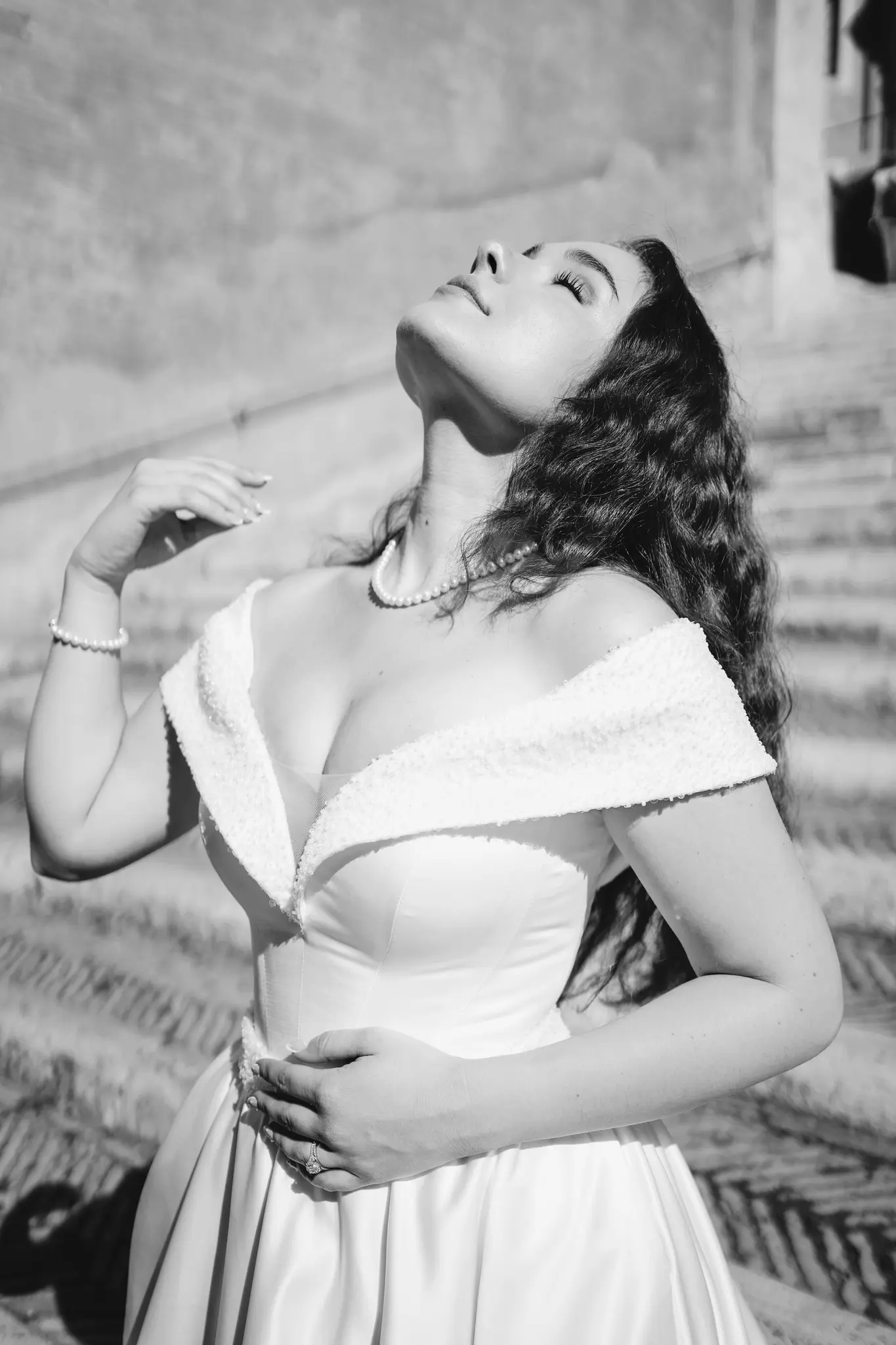 A bride in black and white, tilting her head back to feel the sun on her face.