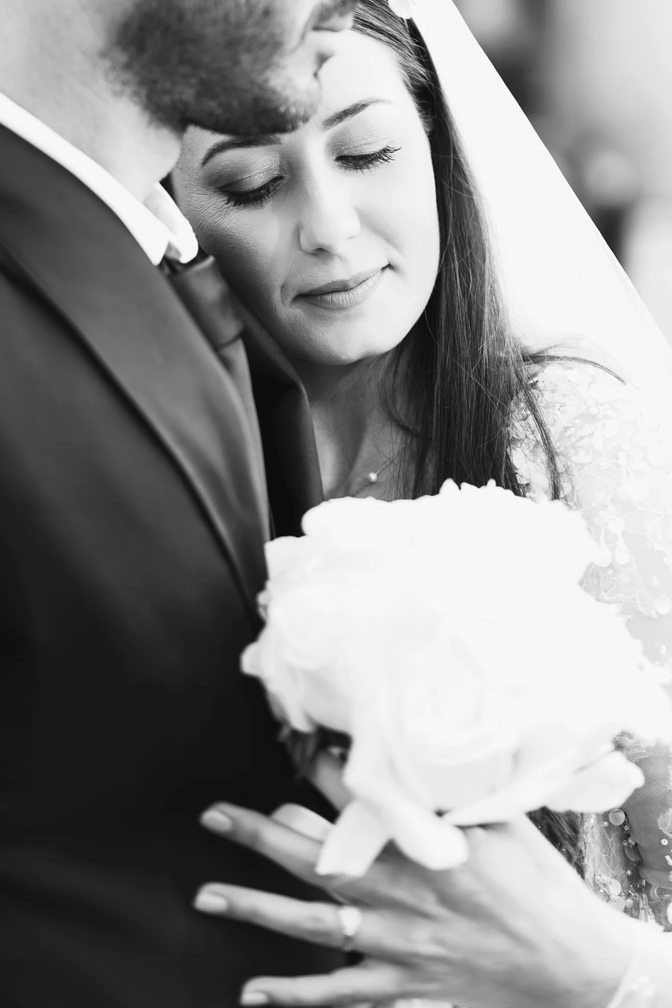 A tender black and white moment of a bride resting on the groom's shoulder.