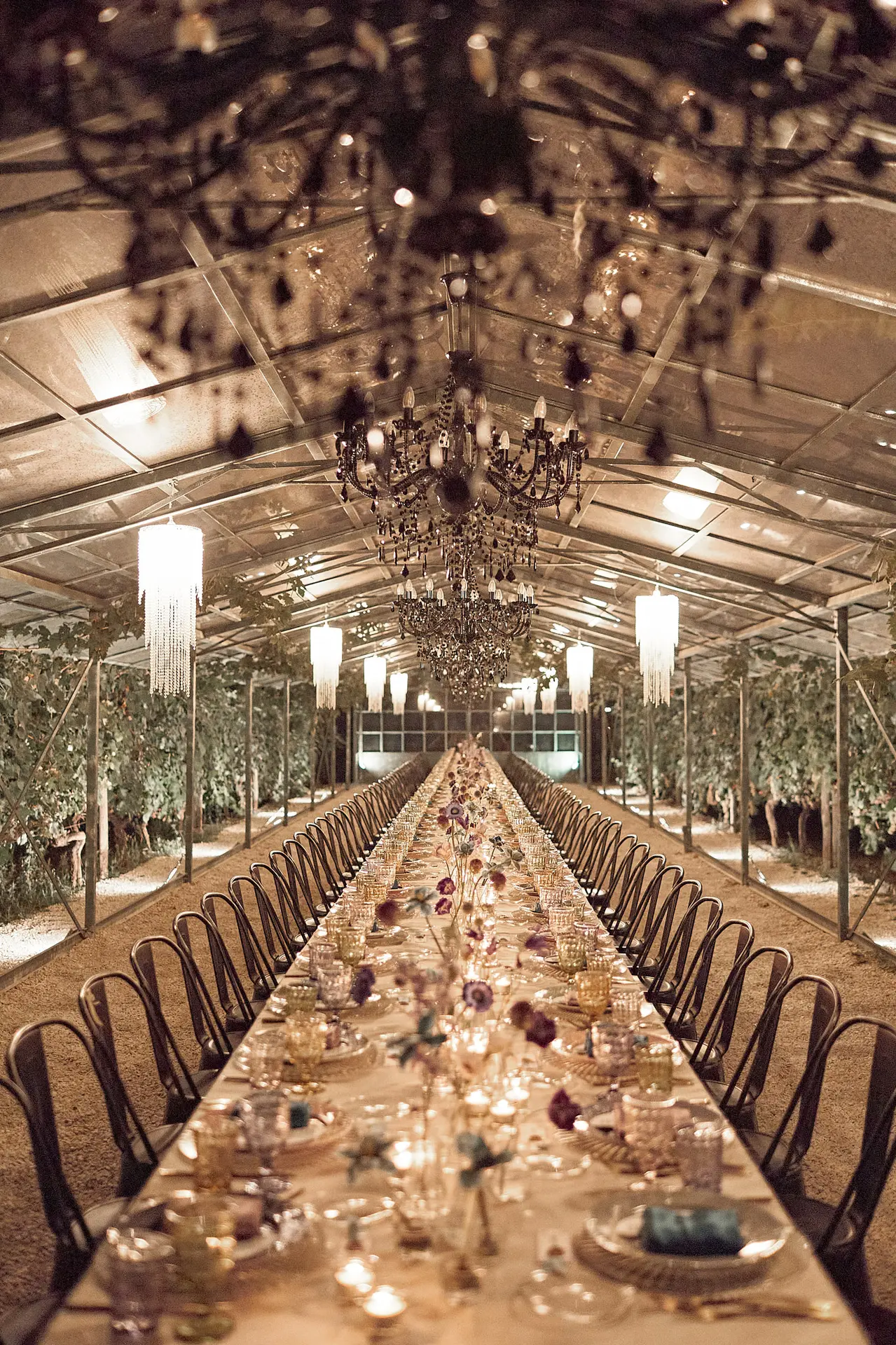 An elegantly decorated long reception table under chandeliers in a marquee.