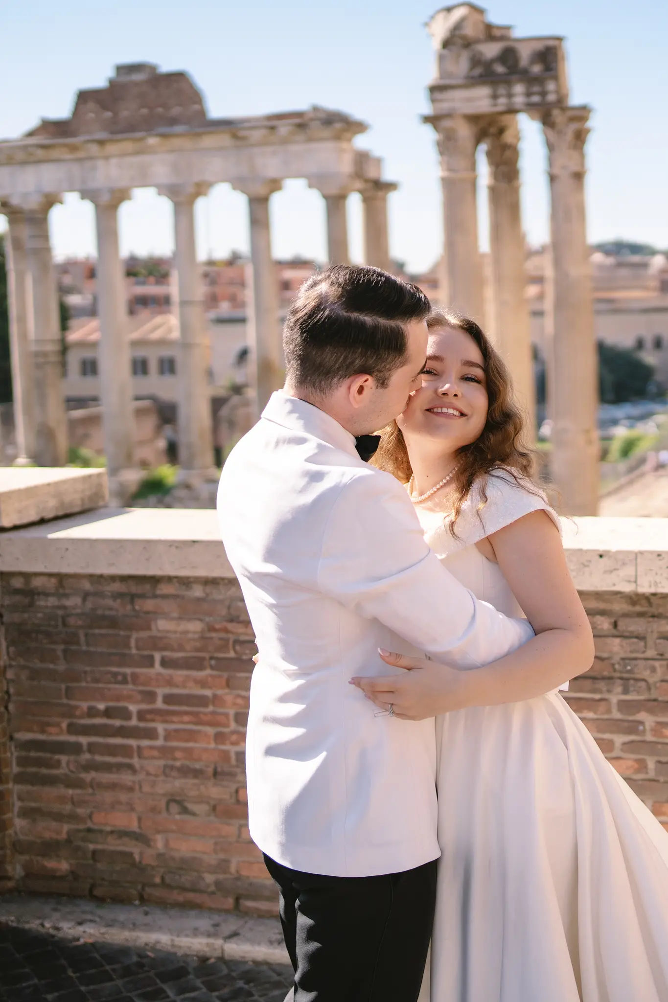 A groom in a white jacket embraces his joyful bride. A perfect moment by a wedding photographer in Rome.
