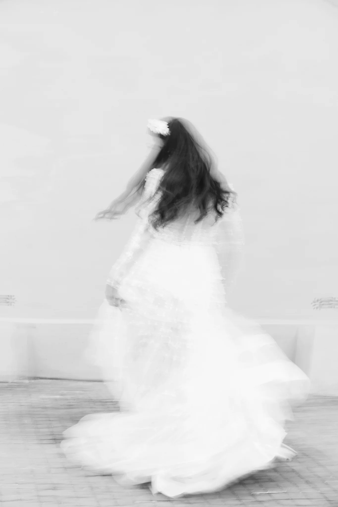 An artistic, black and white shot with motion blur creates an ethereal portrait of a bride in motion.