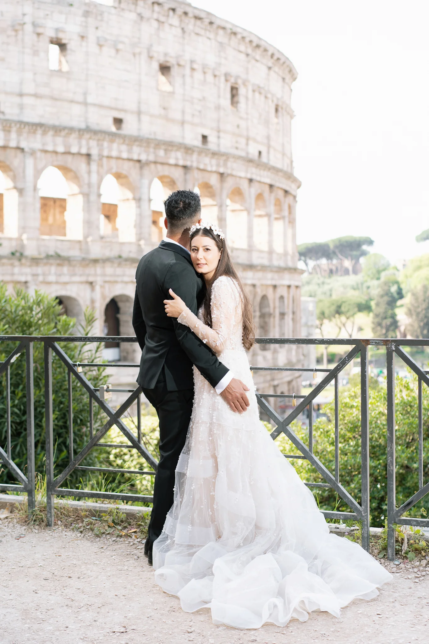 A bride in an elegant gown is embraced by her groom. A classic shot by a wedding photographer in Rome.