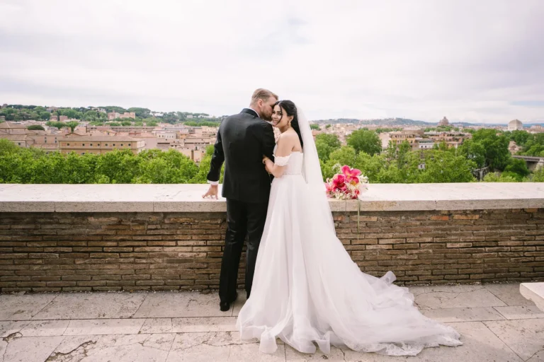 An elopement photographer in Rome captures a couple on a terrace overlooking the city skyline.
